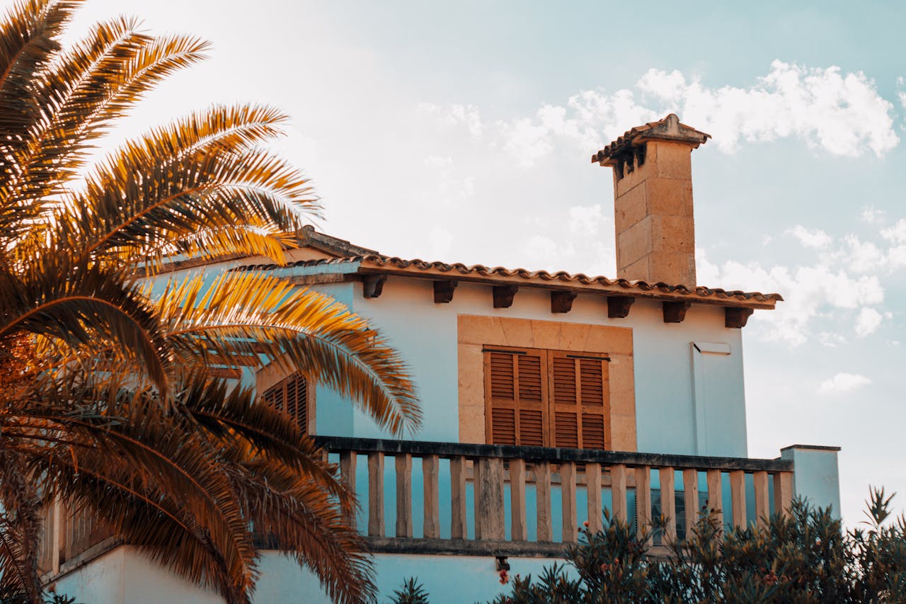 A Mediterranean-style house with a palm tree under a sunny sky in Spain.